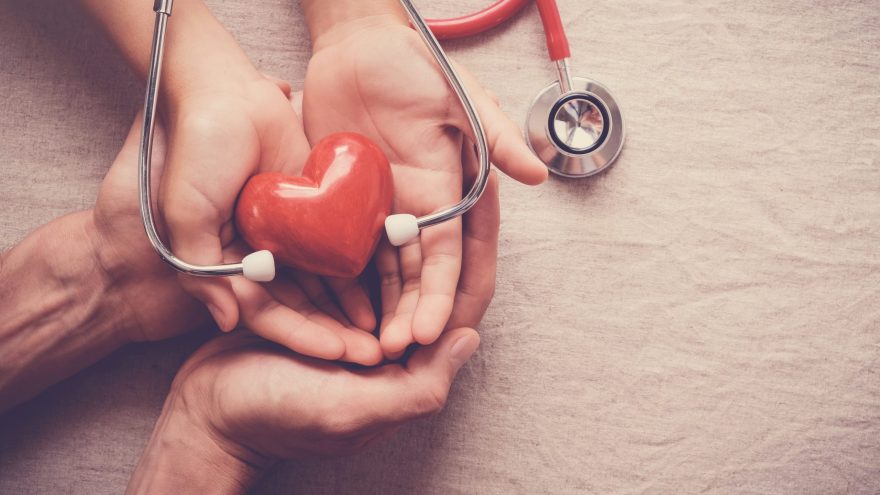 child and adult holding red heart with stethoscope, heart health